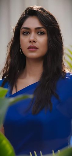 an image of a woman with long hair looking at the camera while wearing a blue dress