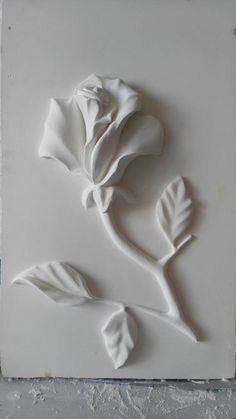 a white tile with a rose on it's side and leaves in the middle