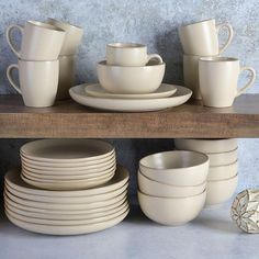 a shelf filled with white dishes and cups