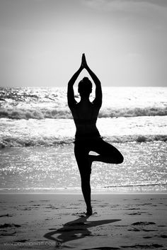 a woman doing yoga on the beach in front of the ocean