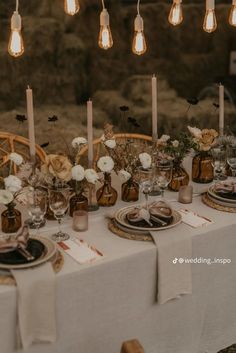 the table is set with candles, plates and place settings for an elegant dinner party