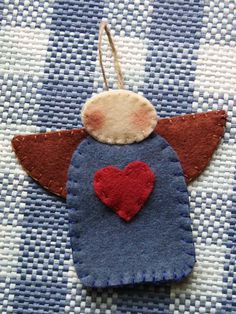 a felt angel ornament with a heart on it's back hanging from a string