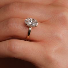 a woman's hand with a diamond ring on her left hand, showing the center stone