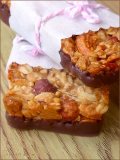 two pieces of chocolate covered fruit and nuts on top of each other in front of a paper bag