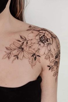 a woman's shoulder with flowers and leaves tattoo on her left arm, in black and white