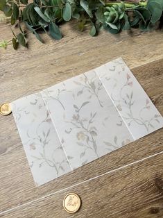 three pieces of paper sitting on top of a wooden table next to green leaves and coins