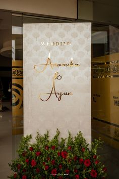 the wedding sign is decorated with gold lettering and red flowers in front of a window