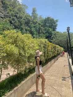 a woman in white shorts and a hat is standing on the edge of a walkway