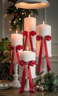 three white candles with red bows on them