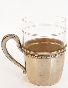 a silver cup filled with liquid on top of a white table