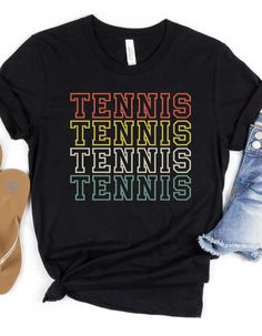 "Get ready for the excitement of fall sports with our \"Tennis\" shirt. Designed with a cute and stylish look, this super soft shirt is perfect for tennis moms and players alike. Whether you're cheering from the bleachers, supporting your team from the sidelines, or showing your pride at practice or school, this shirt ensures you stay comfortable throughout the game. Key Features: Super soft fabric for ultimate comfort Unique and stylish design for a standout look Available in a variety of color Casual Multicolor T-shirt With Team Name, Casual Tennis Tops With Screen Print, Graphic Tee With Letter Print For Tennis, Sporty Pre-shrunk Tennis Tops, Casual Tennis T-shirt Relaxed Fit, Casual Graphic Print Top For Tennis, Sporty T-shirt With Team Name For Tennis, Casual Tennis T-shirt With Team Name, Summer Tennis Tops With Letter Print