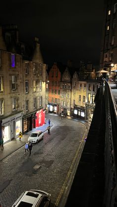 an overhead view of a city street at night with cars parked on the road and people walking around