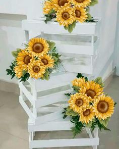 three sunflowers sitting on top of a white wooden shelf next to each other