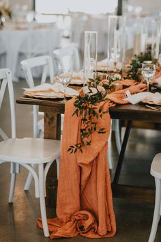 the table is set with white chairs and orange napkins