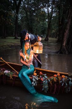 a man and woman are in a boat with a lantern on the water, while another person is holding a lit candle