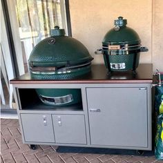 two big green egg grills sitting on top of a table next to a bag of chips