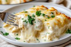 a white plate topped with lasagna covered in gravy and garnished with parsley