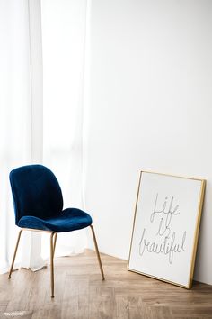 a blue chair next to a sign that says life is beautiful on the floor in front of a window