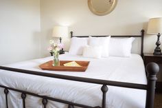 a bed with white sheets and pillows in a bedroom