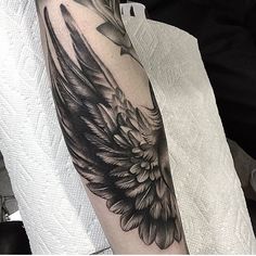 a black and white photo of an angel wing tattoo on the right arm, done by person