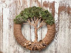 a wreath made out of rope with a tree in the middle on a wooden wall