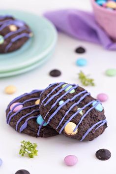 two chocolate cookies with blue icing and sprinkles