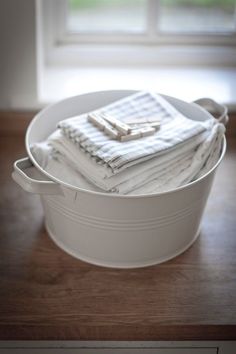 a white bucket filled with cloths on top of a wooden table