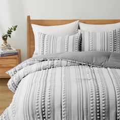 a bed with white and grey striped comforter