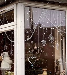 a store front window with ornaments hanging from it's glass and snow falling on the windows