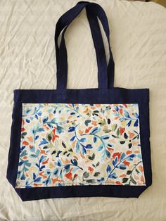 a blue and white tote bag sitting on top of a bed next to a pillow