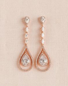 two pairs of diamond earrings on a beige background