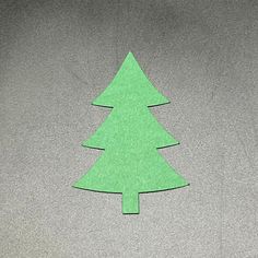 a paper cut out of a green christmas tree sitting on top of a gray floor