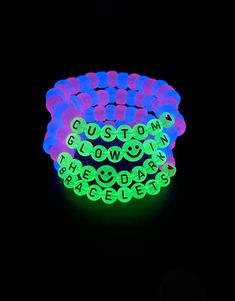 glow in the dark bracelets with smiley faces and words on them, set against a black background