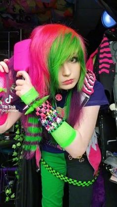 a woman with green and pink hair is holding a cell phone in her hand while wearing neon colored bracelets