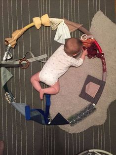 a baby is laying on the floor surrounded by various items that include scissors and hair clips