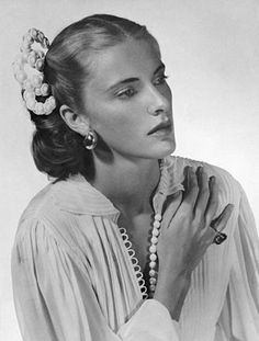 a black and white photo of a woman with pearls in her hair wearing a blouse