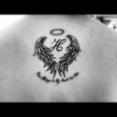 the back of a woman's shoulder with an angel tattoo on her left side