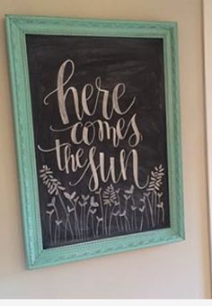 there comes the sun chalkboard sign in green frame hanging on wall next to door