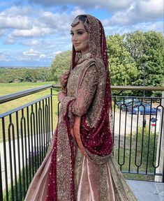 a woman in a red and gold wedding dress standing on a balcony with her arms around her neck