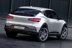 the rear end of a white suv parked in front of a building with glass walls