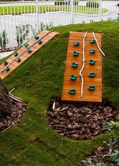 a wooden board laying on top of green grass next to a white fence and trees