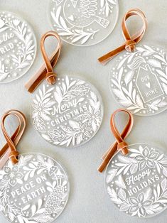 four christmas ornament ornaments with ribbon tied around the top and two tags attached to them