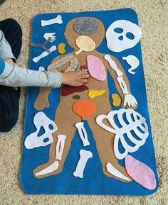 a child is playing with a cut out human body on the floor in front of a rug