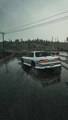 a white car driving down a wet road