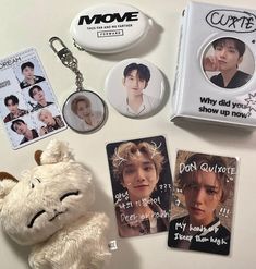 a white teddy bear sitting next to some badges and magnets on a counter top