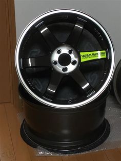 a black and silver wheel on display in a room with wood flooring next to it