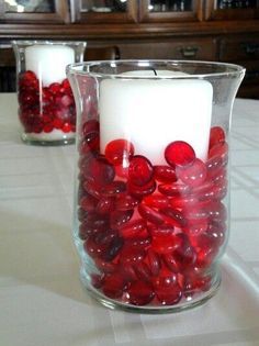 two clear vases filled with red candies on top of a white table cloth