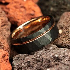 two gold and black wedding bands sitting on top of some rocks with red rocks in the background