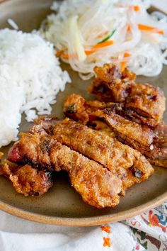 a plate with rice, meat and vegetables on it next to some coleslaw