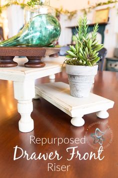 a wooden table topped with two white planters and a green bird on top of it